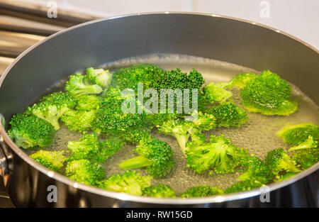 Les blanchir le brocoli à un vert lumineux dans l'eau bouillante Banque D'Images