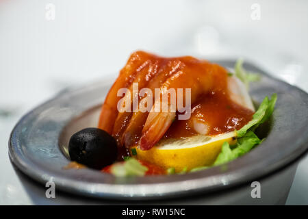 Un nouveau cocktail de crevettes dans un plat en argent avec du citron, de la laitue et une olive noire Banque D'Images