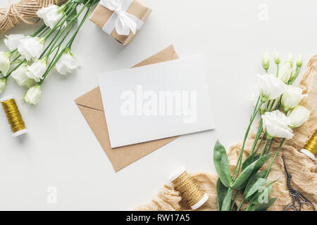 Vue du dessus de l'eustoma, enveloppée, enveloppes cadeaux carte vide, avec des bobines de fil et de tissu sur fond gris Banque D'Images