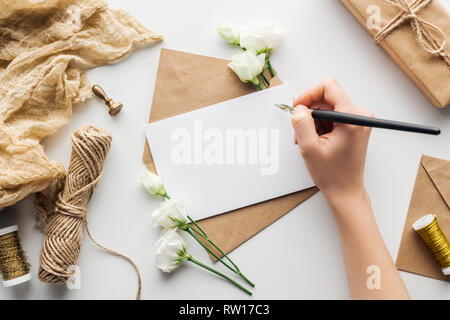 Portrait de femme écrit dans un stylo à encre avec carte près de eustoma, chiffon, enveloppe et l'enveloppa sur fond gris cadeaux Banque D'Images