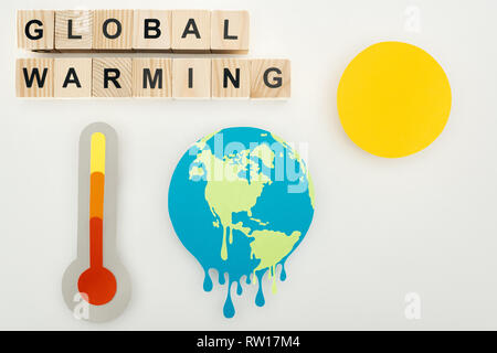 Coupe papier terre et soleil fusion, thermomètre avec indication de température élevée sur l'échelle, et des cubes en bois avec 'le réchauffement climatique' le lettrage sur gray backg Banque D'Images