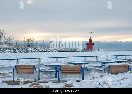 Holland Harbor lighthouse rouge en hiver avec de la glace sur des bancs de parc et tables Banque D'Images