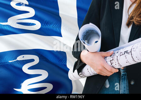 Femme architecte holding blueprint contre Martinique waving flag background. Construction et architecture concept. Banque D'Images