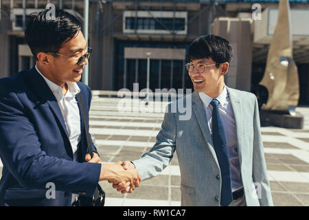 Deux hommes d'affaires se serrer la main à l'extérieur. Asian businesspeople agiter la main à l'extérieur. Banque D'Images