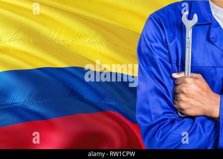 Mécanicien colombien en uniforme bleu clé est contre la Colombie brandissant un drapeau historique. Bras croisés technicien. Banque D'Images