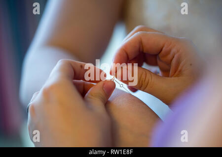 Fermoir de fixation de demoiselle de bracelet sur le poignet de la mariée lors de l'obtention de prêts pour le mariage Banque D'Images