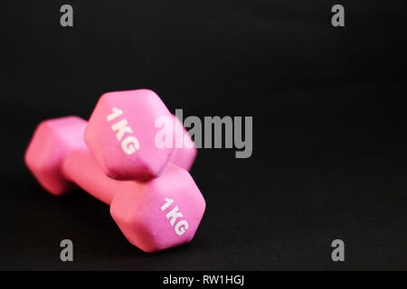 Concept Stay FIT - haltères roses, fond noir, espace de copie gratuit Banque D'Images