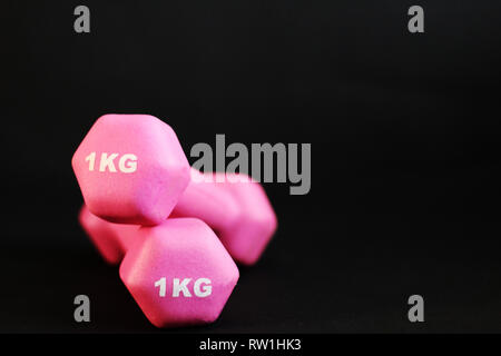 Deux haltères rose gros plan, fond noir, copy space Banque D'Images