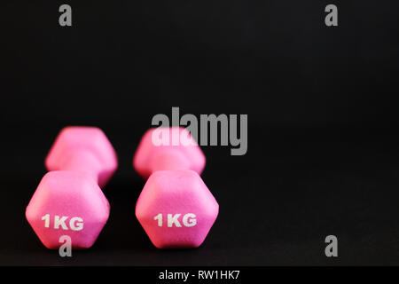 Haltères rose, fond noir, copie gratuite de l'espace, selective focus Banque D'Images