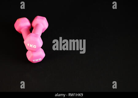 Haltères rose, fond noir, copie gratuite de l'espace, selective focus Banque D'Images