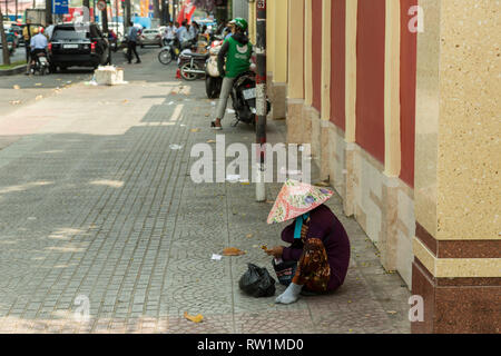 Femme assise dans la rue à Ho Chi Minh, Vietnam Banque D'Images