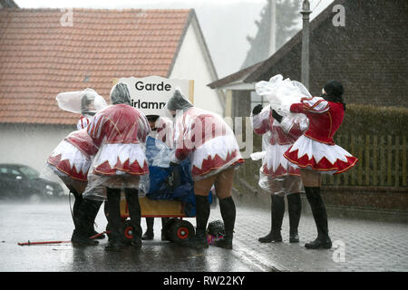 Herbstein, Allemagne. 08Th Mar, 2019. Avant le début de la traditionnelle procession de cavalier, Gardemädchen sont surpris par une forte pluie et tentent de se protéger avec des capes en plastique. Le cavalier train remonte à une ancienne coutume. Au 17e siècle, cette tradition a tailleurs tyrolien à Herbstein. Credit : Uwe Zucchi/dpa/Alamy Live News Banque D'Images