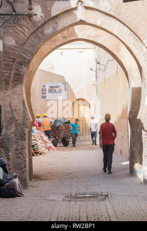 Les trames d'Archway men walking et tirez le panier par ruelle de médina de Marrakech, Maroc Banque D'Images