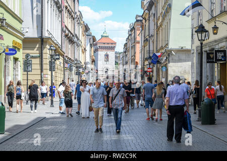 Les gens à la marche et faire eux-mêmes le long des rues pavées de la place du marché principale de Cracovie-w Vieille Ville avec Brama Florianska, mur de la ville, porte b Banque D'Images