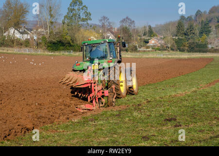 Le labourage DU PRINTEMPS AVEC LE TRACTEUR DANS LE CHAMP VERT DANS LE GLOUCESTERSHIRE ENGLAND UK Banque D'Images