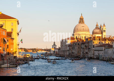 Coucher du soleil sur le Grand Canal et Basilica di Santa Maria della Salute, Venise, Vénétie, Italie avec plusieurs gondoles sur le canal et la lumière d'or chaud Banque D'Images