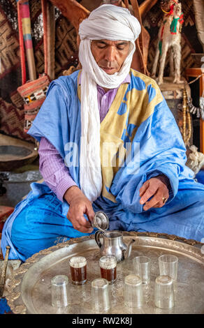 Homme portant un turban et berbère deraa ouvre de couvercle pour théière marocaine traditionnelle cérémonie du thé, Oasis Tighmert, Maroc Banque D'Images