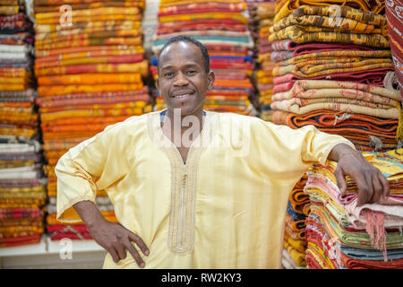 Homme marocain en face de tapis tissé coloré à Ouarzazate, Atlas, Maroc