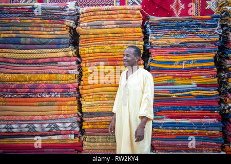 Homme marocain en face de tapis tissé coloré à Ouarzazate, Atlas, Maroc