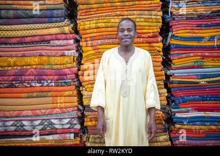 Homme marocain en face de tapis tissé coloré à Ouarzazate, Atlas, Maroc