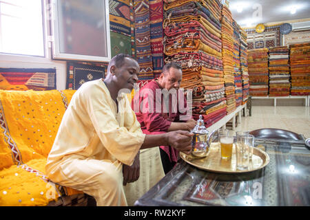 Deux hommes boire le thé ensemble dans une boutique de tapis de luxe, Ouarzazate, Atlas, Maroc
