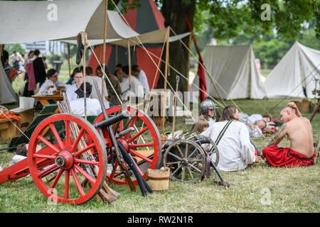 Les festivaliers s'asseoir et se détendre sur le sol et sous tentes avec des armes médiévales éparpillées au congrès annuel de St John's Fair - Jarmark Świętojański - , Banque D'Images