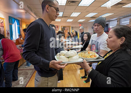 Fidèles à un temple bouddhiste forment une chaîne de montage d'offrir des aliments préparés et cuisinés pour leurs moines. Dans Elmhurst, Queens, New York Banque D'Images