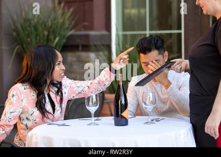 Couple sur une date en colère contre une serveuse dans un restaurant en plein air. Ils sont mécontents et insatisfaits de la service à la clientèle ou la nourriture dans le café. E Banque D'Images