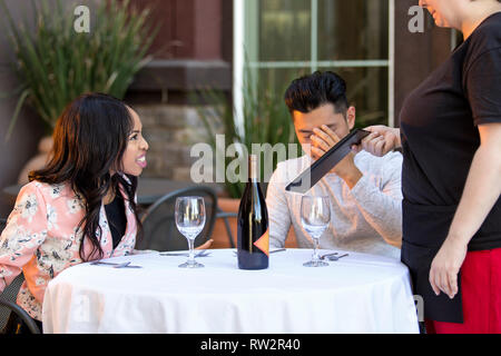 Couple sur une date en colère contre une serveuse dans un restaurant en plein air. Ils sont mécontents et insatisfaits de la service à la clientèle ou la nourriture dans le café. E Banque D'Images