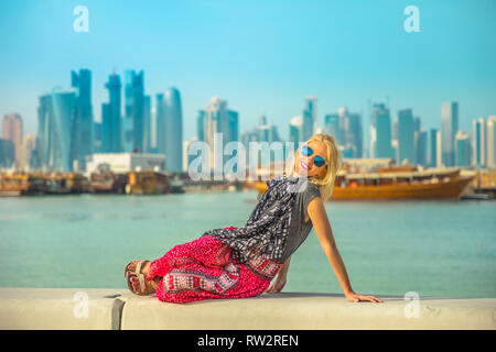 Happy woman relaxing le long de la promenade de la Corniche de Doha et du port de boutres West Bay skyline sur arrière-plan. Touristiques vie bénéficie d à Doha Banque D'Images
