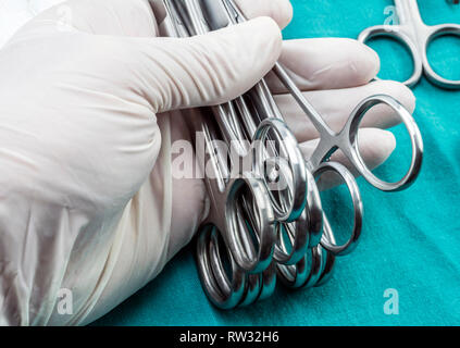 Chirurgien travaillant en salle d'opération, les mains avec des gants holding scissors sutures, conceptual image, composicon l'horizontale Banque D'Images