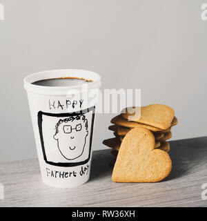 Libre d'un gobelet jetable avec café, avec le texte happy fathers day écrits en C, et certains cookies en forme de cœur sur une table Banque D'Images