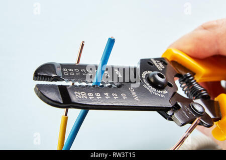 L'électricien utilise un cutter pour dénuder les fils pendant les travaux d'électricité, close-up. Banque D'Images