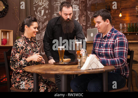 Hipster barman responsable de l'ordre de belle jeune couple.Grande Pub. Banque D'Images