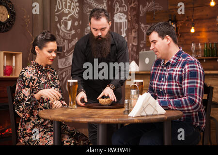 Hipster barman responsable de l'ordre de belle jeune couple.Grande Pub. Banque D'Images