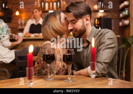 Belle femme chuchote à son beau petit ami oreille combien elle l'aime. Beau couple Banque D'Images