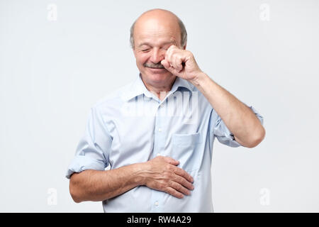 Insatisfait déconcertés senior man de pleurer et d'essuyer les larmes isolé en studio. Les gens sincères émotions, style de concept. Banque D'Images