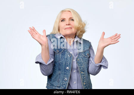 Portrait of a senior woman having nice un doute de geste. Qui sait ou je ne sais pas quoi choisir. Banque D'Images