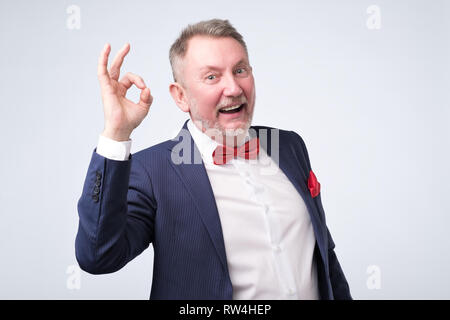 Man costume bleu élégant montrant OK signe. Il est d'accord avec votre choix. L'émotion positive. Banque D'Images