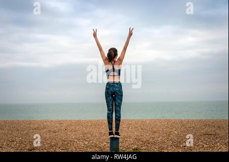 Femme debout avec les bras levés, sur la plage, vue de dos, copyspace Banque D'Images