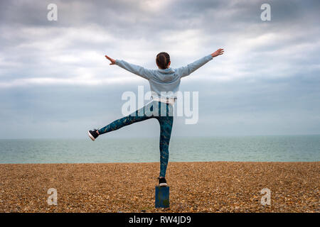 Femme debout avec les bras levés, sur la plage, vue de dos, copyspace Banque D'Images