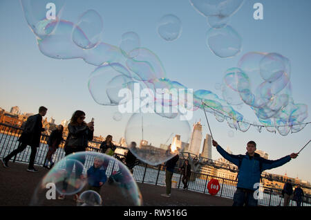 Les enfants chasse et bulles qui faites par l'artiste de rue sur la rivière Thames Embankment, London, UK. Banque D'Images