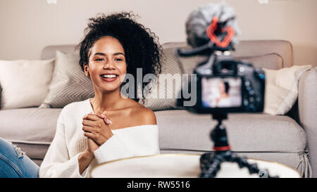 Happy female vlogger live streaming à partir de la salle de séjour à l'aide de votre appareil photo reflex numérique Banque D'Images