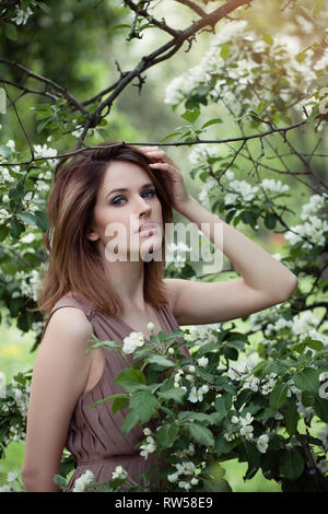 Belle femme dans le jardin des fleurs. Fille sur fond de fleurs apple outdoors Banque D'Images