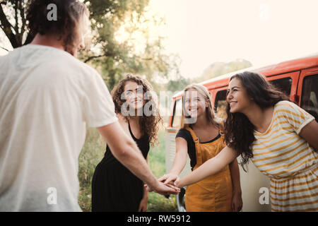 Un groupe de jeunes amis sur un roadtrip à travers campagne, mettant les mains ensemble. Banque D'Images