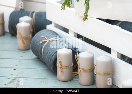 Belles couvertures pliées et décoratives bougies blanches contre des caisses en bois peint en blanc. Il tous les stands sur le plancher en bois bleu Banque D'Images