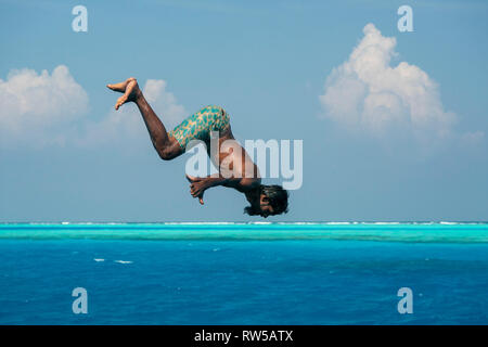 Jeune homme aux Maldives plongée plongée de bateau dans les eaux cristal turquoise Banque D'Images