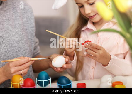 Mère et fille peinture oeufs de Pâques à la maison Banque D'Images