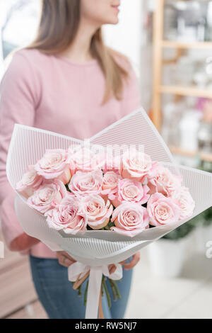 Bouquet de roses dans les mains des femmes. Bouquet rose pâle. Le concept d'un fleuriste dans un magasin de fleur. Fond d'écran. Banque D'Images