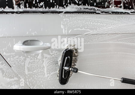 Côté de l'argent un architecte en self service carwash, brosses de nettoyage mousse shampooing. Banque D'Images